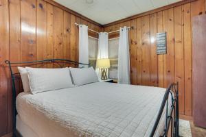 een bed in een kamer met houten lambrisering bij Roscommon Cabin, Walk to Higgins Lake in Roscommon