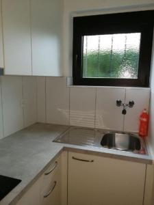 eine kleine Küche mit einem Waschbecken und einem Fenster in der Unterkunft Casa Adelizia - Erdgeschoss - b48561 in Ascona