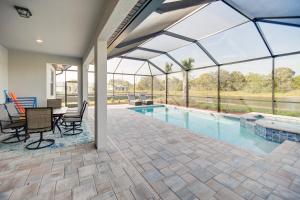 um pátio com uma piscina, uma mesa e cadeiras em Alva Vacation Rental with Pool and Golf Course Access! em Lehigh Acres