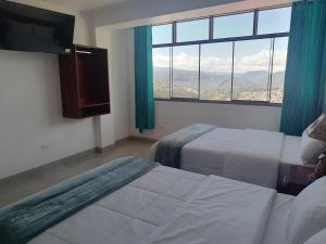 a hotel room with two beds and a large window at HOSTAL EL MIRADOR CHACHAPOYAS in Chachapoyas