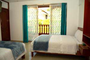 a bedroom with a bed and a window with blue curtains at HOSTAL EL MIRADOR CHACHAPOYAS in Chachapoyas