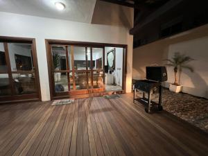 a living room with a wooden floor and a tv at Casa na Praia Riviera de São Lourenço 4 Suítes para até 12 pessoas 4min a pé da Praia e 11 min a pé do Shopping in Riviera de São Lourenço