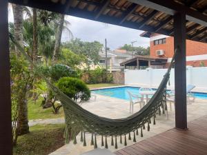 a hammock on a porch next to a pool at Casa na Praia Riviera de São Lourenço 4 Suítes para até 12 pessoas 4min a pé da Praia e 11 min a pé do Shopping in Riviera de São Lourenço