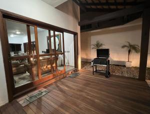 an empty living room with a piano in a room with glass doors at Casa na Praia Riviera de São Lourenço 4 Suítes para até 12 pessoas 4min a pé da Praia e 11 min a pé do Shopping in Riviera de São Lourenço