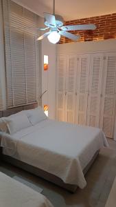 a bedroom with a white bed and a ceiling fan at Hermoso Apto en el corazón de la ciudad amurallada in Cartagena de Indias