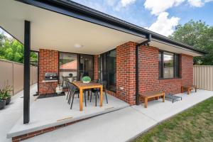 an extension to a brick house with a table and benches at MèRose Place - Spacious Modern New in Bathurst