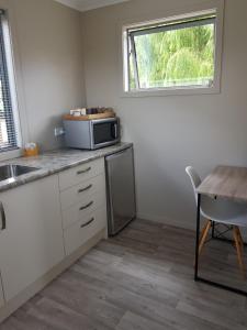 a kitchen with a microwave and a table and a window at Lookout Studio in Alexandra