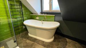 y baño con bañera y paredes verdes. en The Coach House - Your luxury private Brighton getaway with private parking en Brighton & Hove