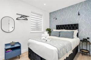 a bedroom with a large bed with a blue accent wall at Luxury Entire Apartment in Cowley