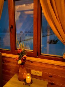 un vaso con fiori e una candela su un tavolo accanto a una finestra di Blue Village 8 a Kolašin