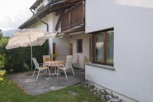 a patio with a table and chairs and an umbrella at Casa Marianne - b48614 in Flims