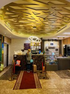 a woman sitting at a counter in a hotel lobby with luggage at فندق زهرة الربيع zahrat alrabie Hotel in Jeddah