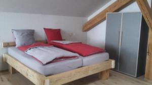 1 dormitorio con 1 cama con almohadas rojas y nevera en Bijou - BioBergün - b48615, en Bergün