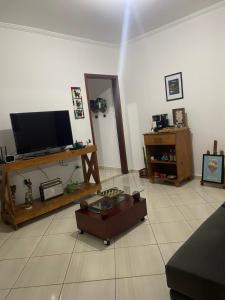 a living room with a flat screen tv on a table at Homeoffice Central 1 quarto 1 cama de casal banheiro privativo in Alfenas
