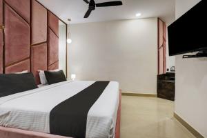 Astra Hotels & Suites - Koramangala في بانغالور: غرفة نوم بسرير وتلفزيون بشاشة مسطحة