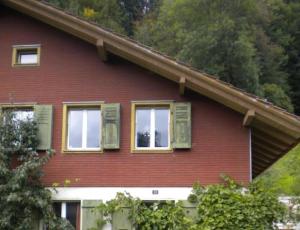 une maison rouge avec des fenêtres à volets verts dans l'établissement EmmeCottage - b48613, à Trubschachen