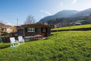 a small cabin in a field with two chairs in the yard at Bauernhof - Familienzimmer - b48580 in Lungern