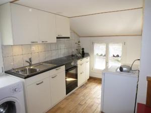 cocina con armarios blancos, fregadero y lavavajillas en Ferienwohnung Langberg - b48588, en Lauerz