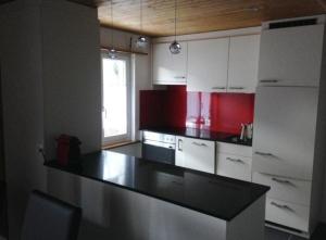 eine Küche mit weißen Schränken und einer schwarzen Arbeitsplatte in der Unterkunft Sonnige und saubere Ferienwohnung Selunblick im schönen Toggenburg - b48571 in Alt Sankt Johann