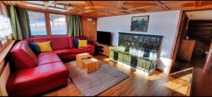 a living room with a red couch and a fireplace at Gemütliche und geräumige Ferienwohnung - b48625 in Nesslau