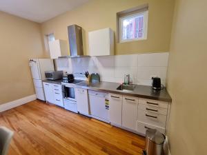 cocina con electrodomésticos blancos y suelo de madera en Dunedin City Centre Apartment Room B, en Dunedin