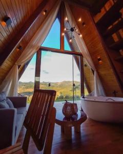 Zimmer mit einem großen Fenster und einer Badewanne in einer Hütte in der Unterkunft Cabana em Domingos Martins in Domingos Martins