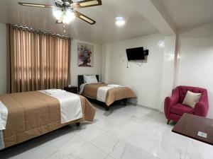 una habitación de hotel con 2 camas y una silla en HOSTAL ARICA CAJABAMBA, en Cajabamba