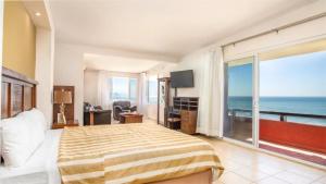 a bedroom with a bed and a view of the ocean at Puerto Nuevo Baja Hotel & Villas in Rosarito