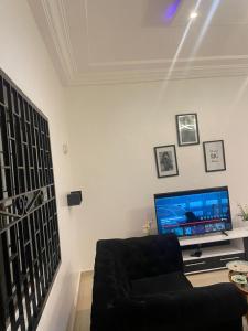 een woonkamer met een bank en een flatscreen-tv bij Guest house in Cotonou