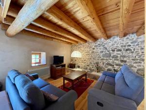 ein Wohnzimmer mit blauen Sofas und einer Steinmauer in der Unterkunft Gîte Saint-Vert, 5 pièces, 7 personnes - FR-1-582-230 in Saint-Vert