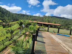 une passerelle en bois menant à un pavillon avec des montagnes en arrière-plan dans l'établissement Sítio do Vicente @sitiodovicenteop, à Ouro Preto