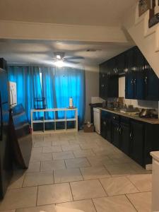 una grande cucina con tende blu e un grande pavimento piastrellato di Nice & Spacious House in Silsbee w/ Self Check-in a Silsbee