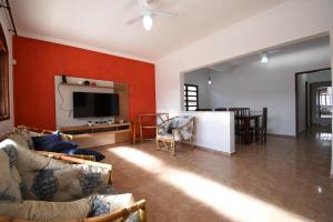 a living room with red walls and a tv and a couch at CASA PERUIBE in Peruíbe