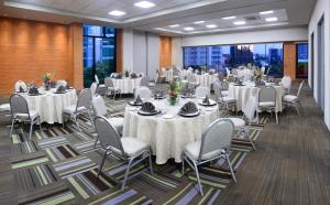 un salón de banquetes con mesas y sillas blancas y ventanas en Hotel Guadalajara Country Club by HNF, en Guadalajara