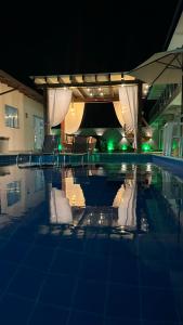 una piscina por la noche con sillas y sombrilla en Isadora Pousada en Salinópolis