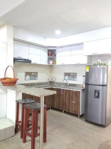 una cocina con nevera de acero inoxidable y armarios de madera en Casa confortable 3 min del centro de Funza zona de tranquilidad, en Funza