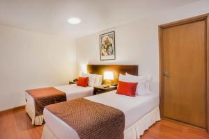 a hotel room with two beds and a door at Hotel Oceanía Bogotá Museo in Bogotá