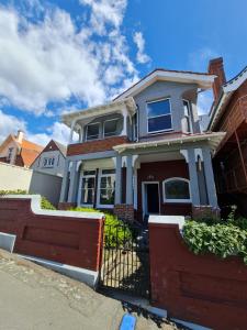 a house with a red fence in front of it at Dunedin City Centre Apartment Room B in Dunedin