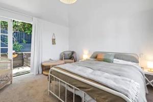 a white bedroom with a large bed and a window at Seaglass Cottage in Lower Hutt