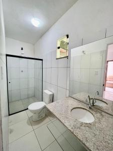 a white bathroom with a toilet and a sink at Hostel Pipe House in Ilhéus