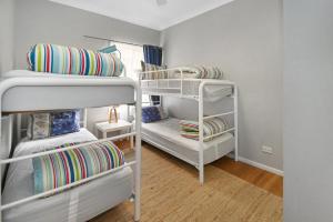 a room with three bunk beds and a couch at Mar-Lin cute beach house in Callala Beach