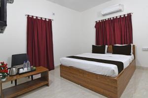 a bedroom with a large bed with red curtains at OYO Hotel Bijaya Premium in Bhubaneshwar