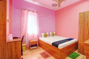 ein Schlafzimmer mit einem Bett und einer lila Wand in der Unterkunft OYO Hotel Divyanka Lodge in Guwahati