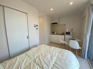 荒尾市にあるTHE LAND HOTEL - Vacation STAY 89073vの白いベッドルーム(ベッド1台付)、キッチンが備わります。