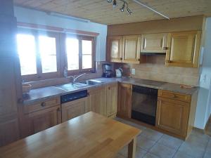 a kitchen with wooden cabinets and a sink and a table at Steffelhüs 8-Bettwohnung - b48637 in Hasliberg