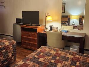 a hotel room with a desk with a computer and a bed at Cortland Motel in Cortland