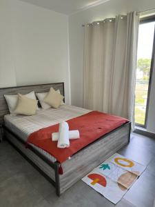 ein Schlafzimmer mit einem Bett mit einer roten Decke und einem Fenster in der Unterkunft Sandstone Apartment a walk to the beach in Flic-en-Flac