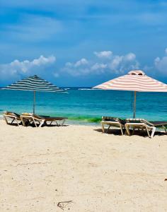 dos sombrillas y sillas en una playa con el océano en Sandstone Apartment a walk to the beach, en Flic en Flac