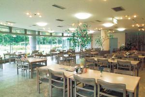 un restaurant avec des tables et des chaises en bois ainsi que des fenêtres dans l'établissement Horoshin Onsen Hotarukan, 