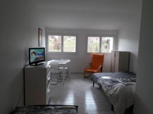 a room with two beds and a desk with a computer at Studio cosy en cœur de La Roche-Posay, proche Thermes, Wi-Fi, laverie, tout équipé - FR-1-541-84 in La Roche-Posay